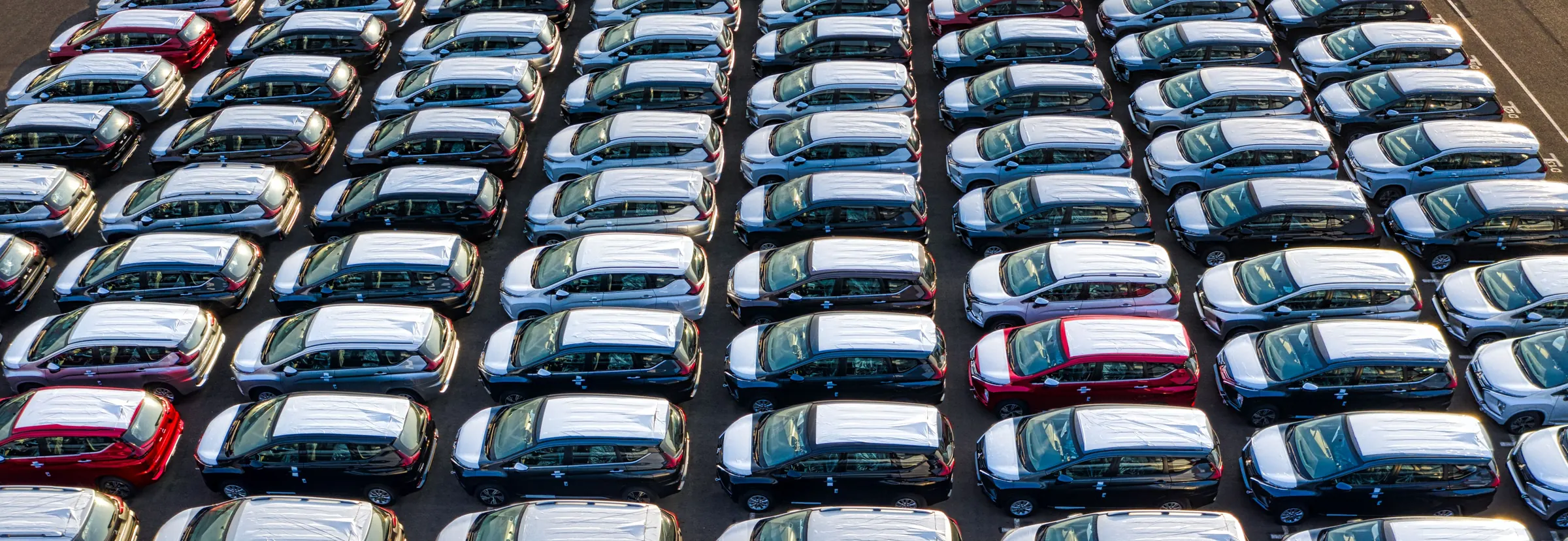 Aerial view of rows of new cars parked close together in a vehicle lot