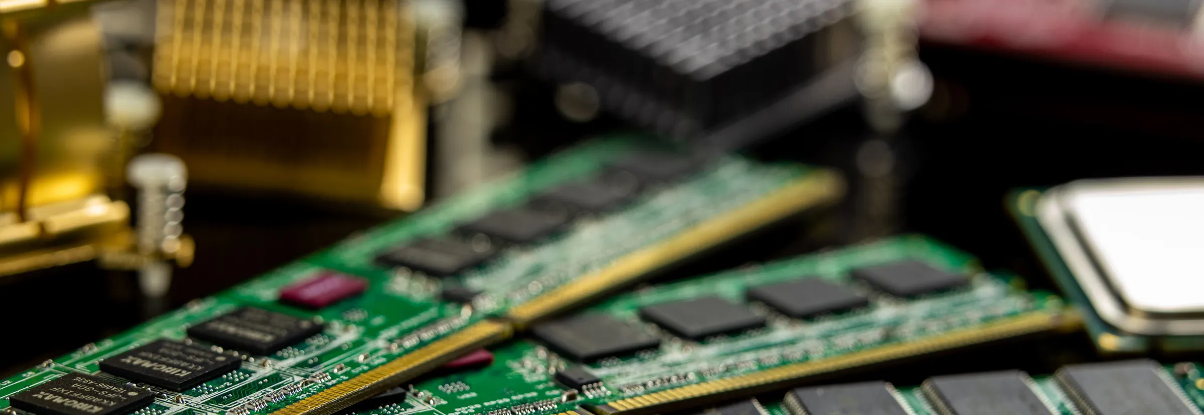 Green memory modules fanned out on a dark circuit board, with a heat sink and a processor out of focus behind them