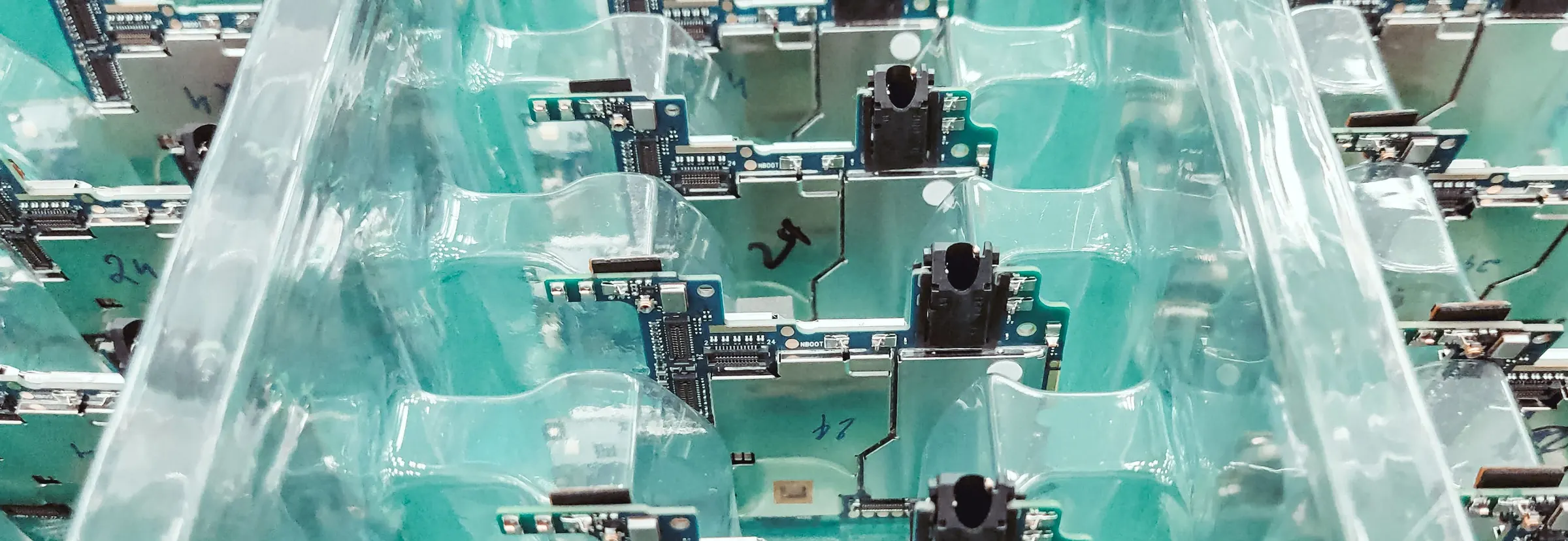 Electronic circuit boards stacked in clear plastic trays on a production line