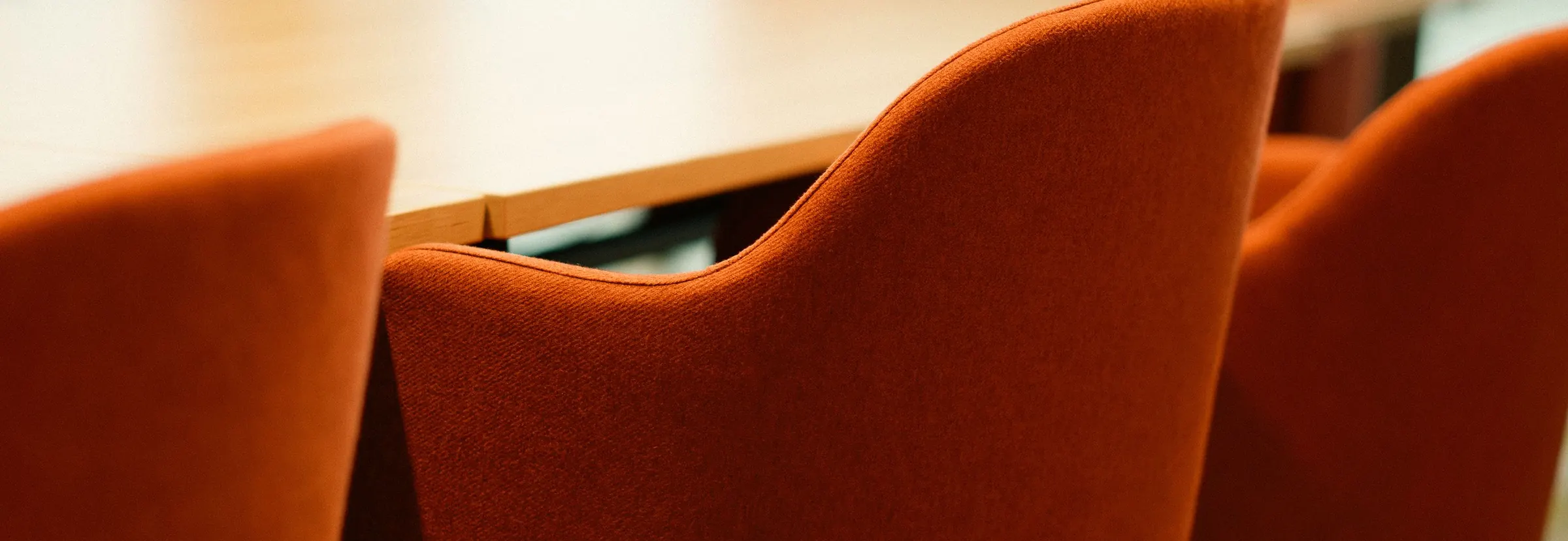 Orange upholstered chairs around a wooden boardroom table