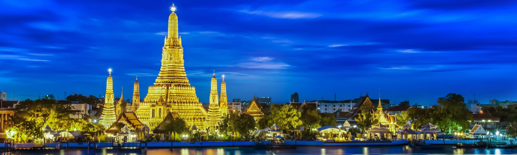 Wat Arun lit up at dusk on the bank of the Chao Phraya River in Bangkok
