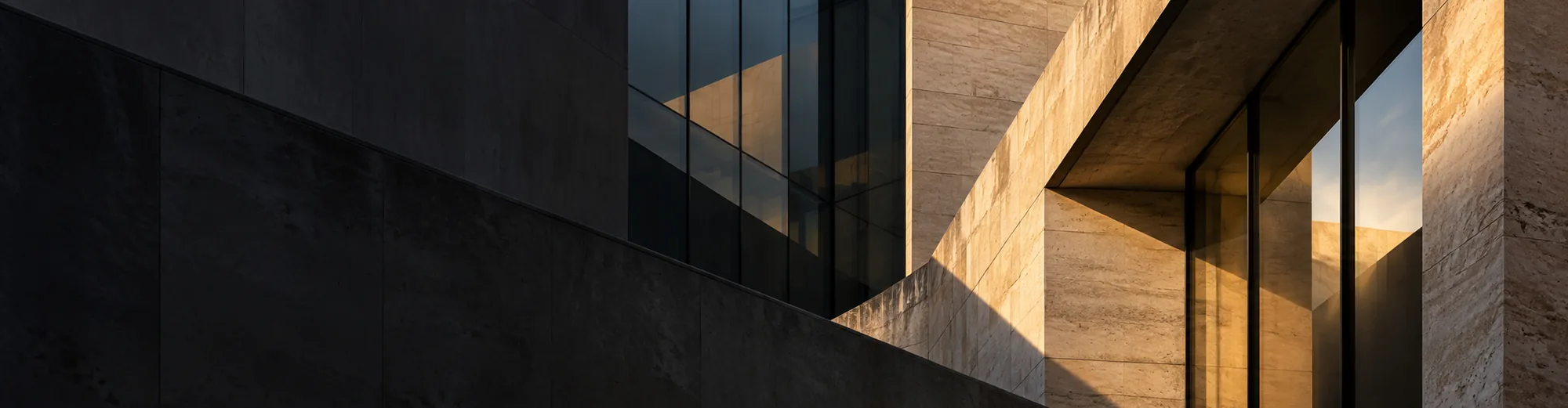 Stone and glass building walls in low sunlight, with deep shadows