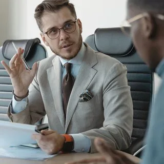 A man in a suit talking in an interview across a table