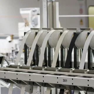 White rollers and guides lined up on a production machine in a factory