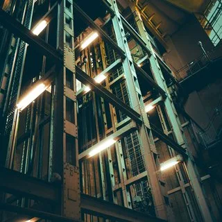 View up an elevator shaft lined with steel beams and lights
