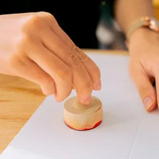 A hand pressing a rubber stamp onto a document